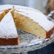 Delicious limoncello ricotta cake, sliced, on a glass cake stand.