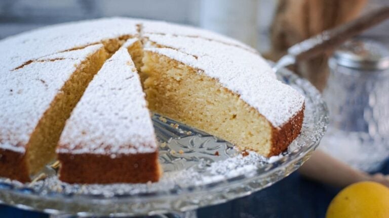 Delicious limoncello ricotta cake, sliced, on a glass cake stand.