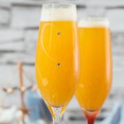 Beautiful champagne flutes, filled with delicious peach Bellini. Placed on blue, wooden ground.