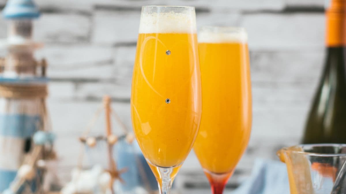 Beautiful champagne flutes, filled with delicious peach Bellini. Placed on blue, wooden ground.
