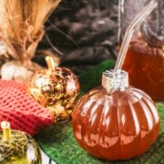 Homemade spiced apple cider in pumpkin shaped drinking glass.