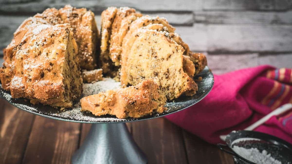 Delicious vanilla bundt cake with chocolate sprinkles, served on light blue cake stand.