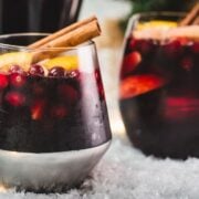 Gorgeous glass filled with delicious winter sangria, garnished with a cinnamon stick. Placed on snow covered ground.